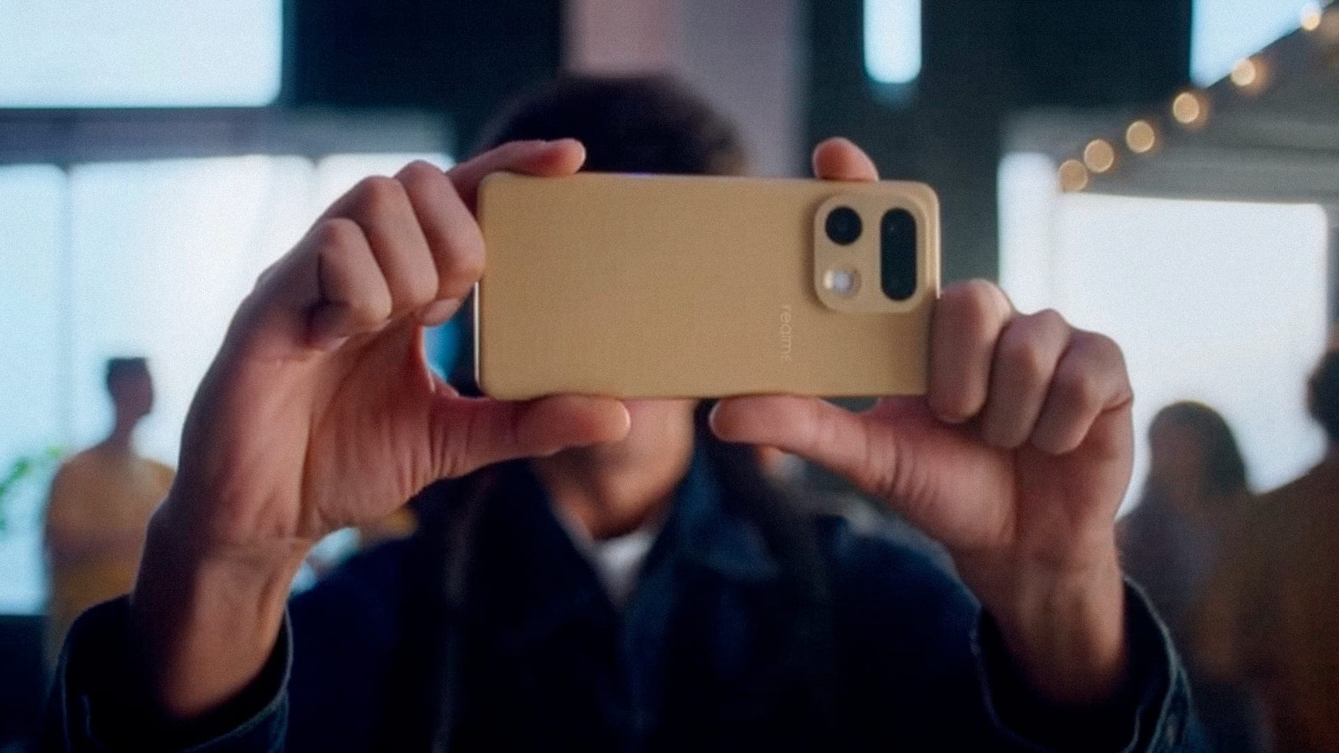 Hands holding a phone sideways to film, a warm bar interior soft behind it